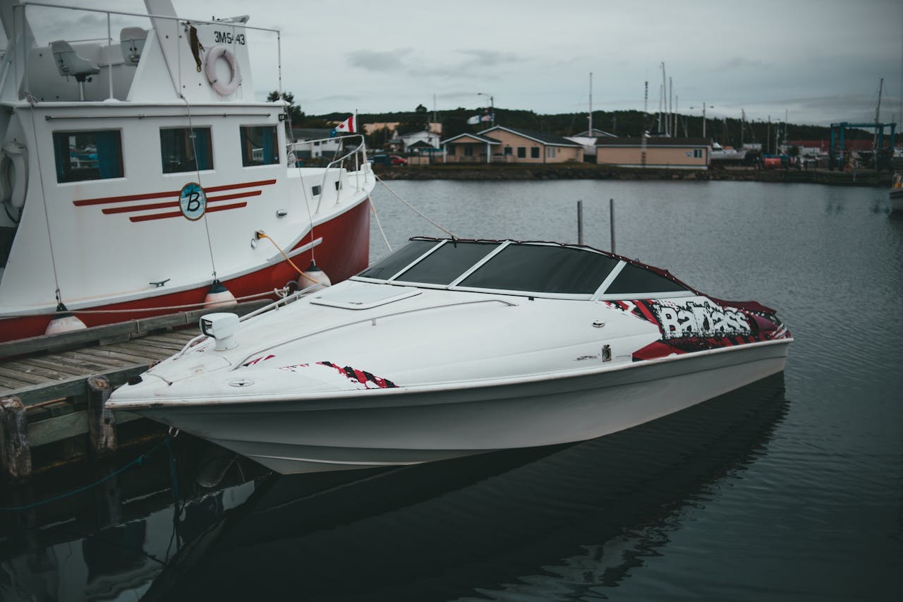 A sleek motorboat docked peacefully beside a larger boat in a quiet harbor setting.